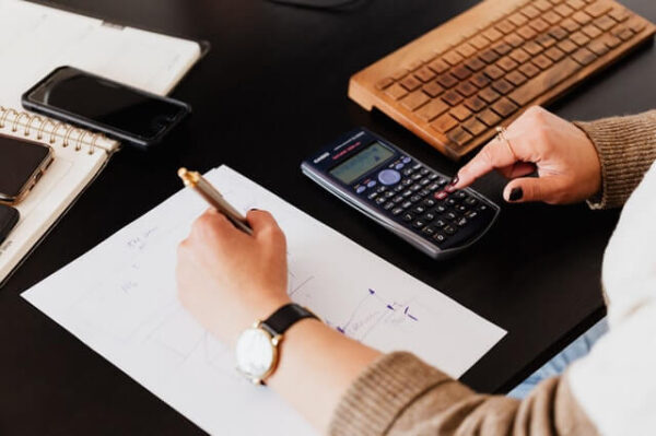 Working through financial records with a calculator and notebook